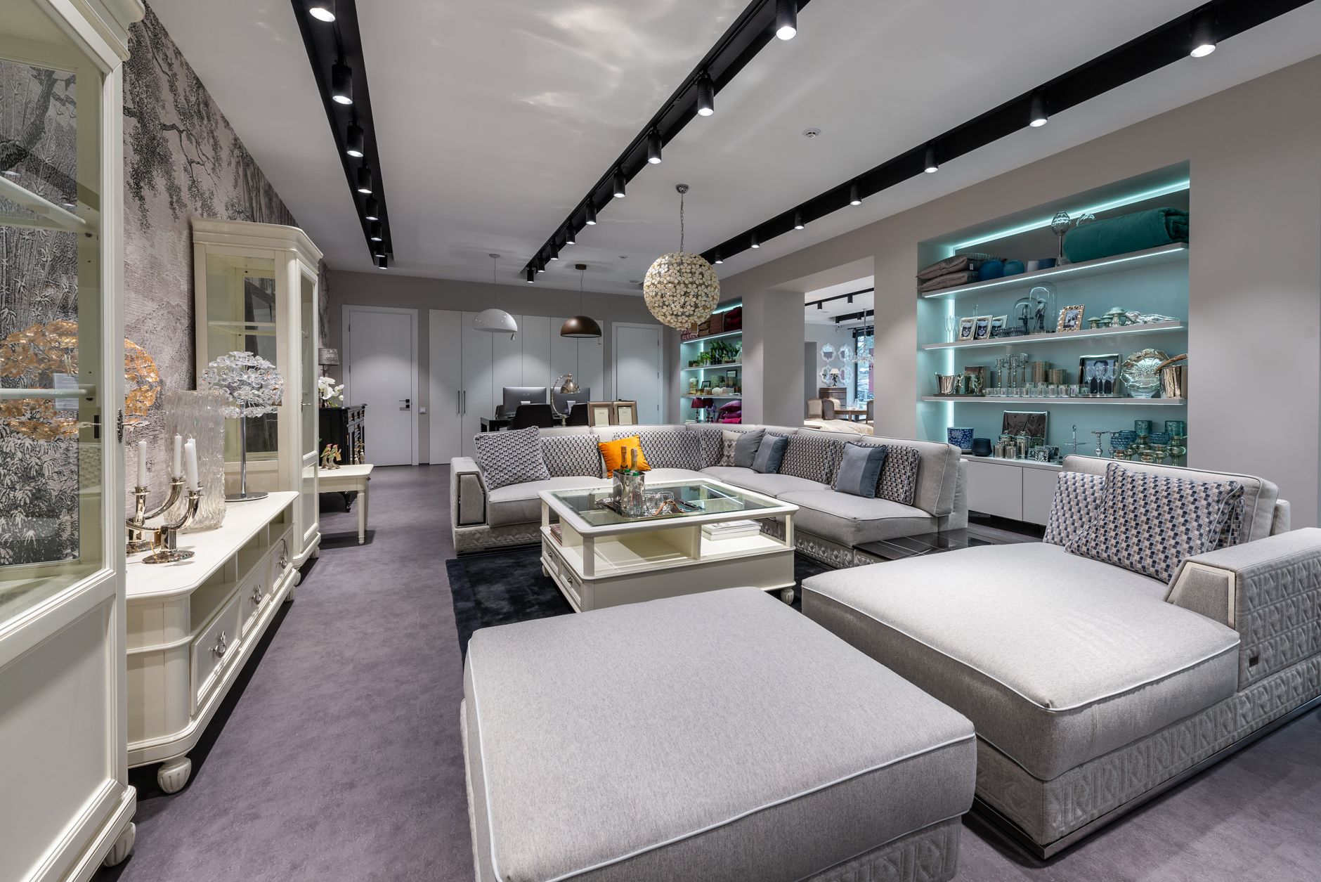 Comfortable sofa with cushions near table placed in spacious modern apartment with white cabinet and various decorative eleme