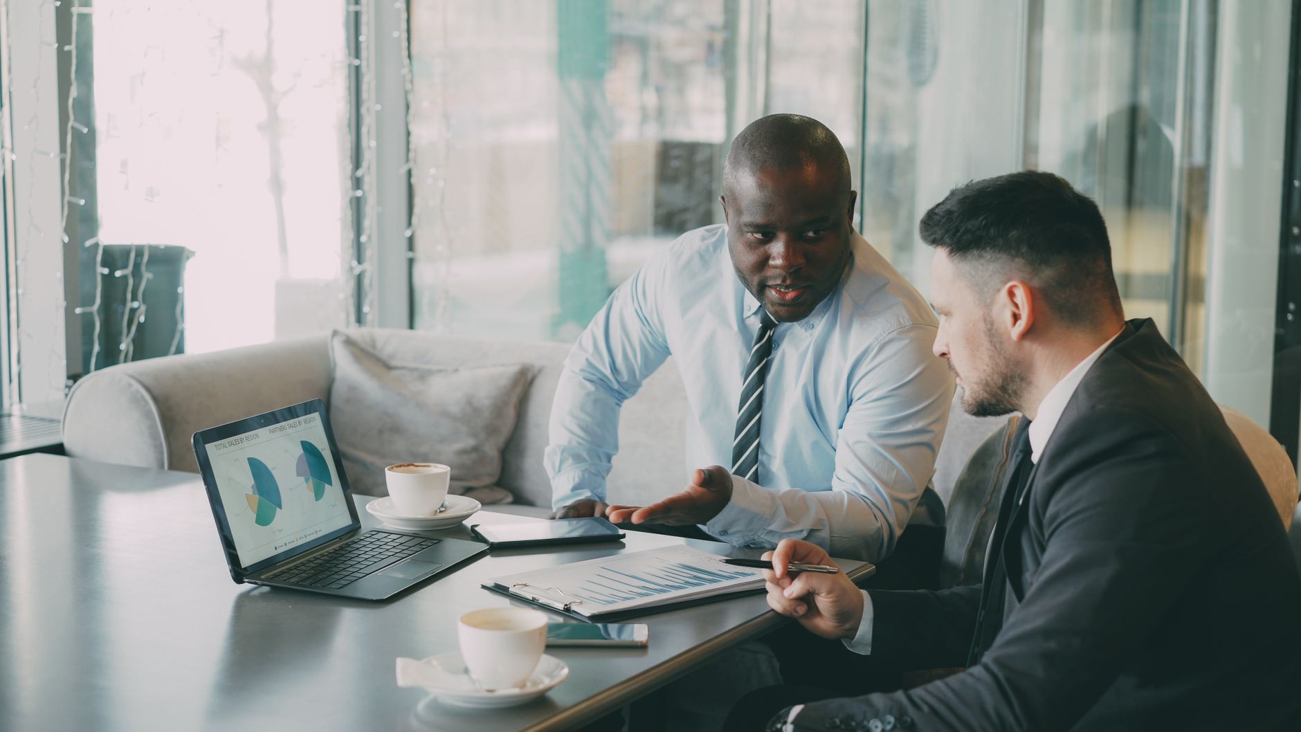 Two businessmen discussing data at a cafe while enjoying coffee. — High-Quality Acoustic Panel for Offices, Recording Studios