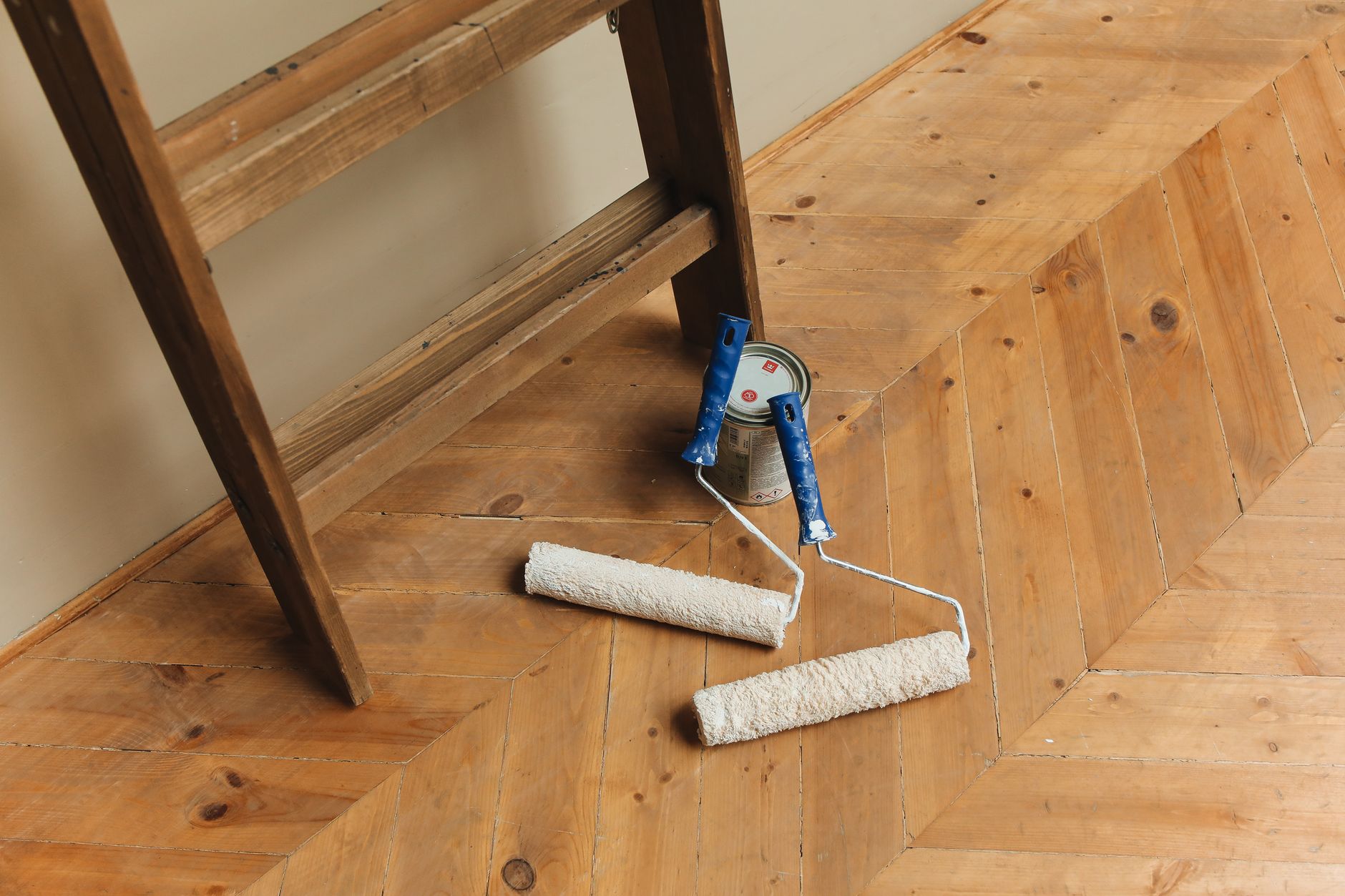 Paint rollers and ladder on a wooden floor, perfect for DIY renovation projects. — Rain gutter guards? You might want to thin