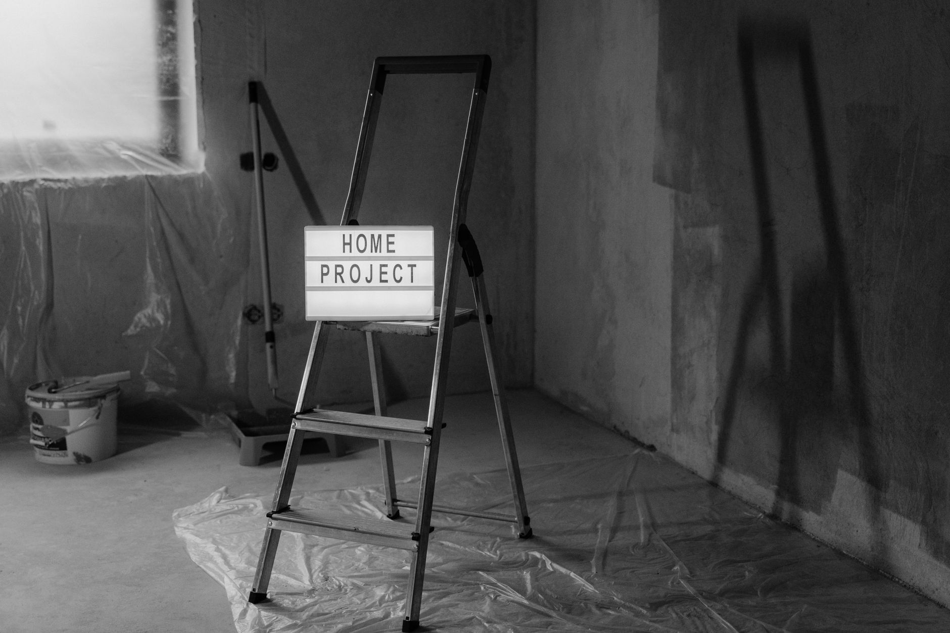 Black and white image of a step ladder with a 'home project' sign in a renovation setting. — Smart and Easy Tips to Maintain