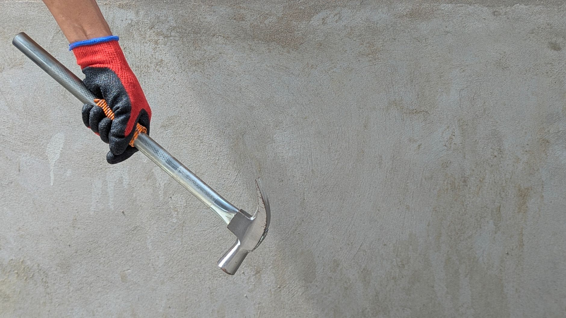 A gloved hand holding a claw hammer against a concrete wall, ideal for construction themes. — The View New Build Apartments i