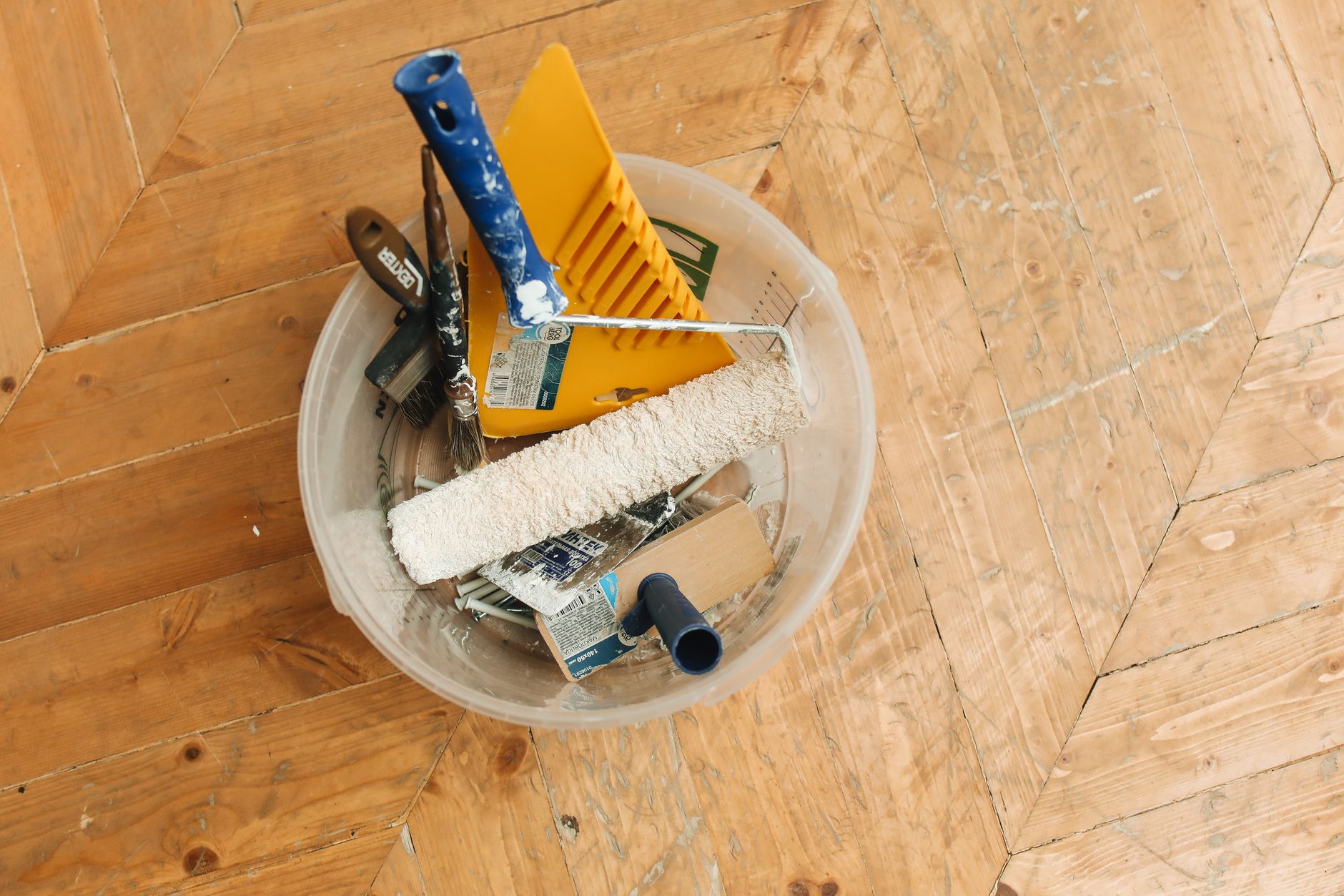 A collection of home renovation tools in a bucket on a wooden floor, ready for a painting project. — Why and How of the Fire